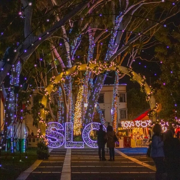 A pedestrian lane in downtown San Luis Obispo decorated with lighted archways. The path leads to a big lit up “SLO” sign.